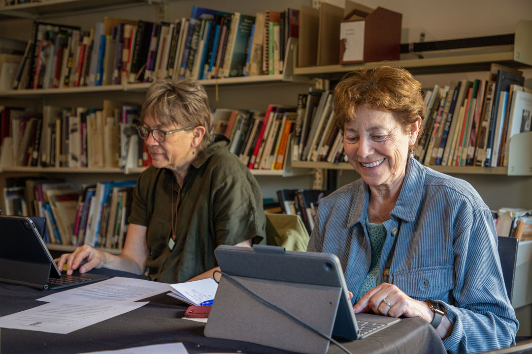 two middle aged women using tablet devices in an engaged matter