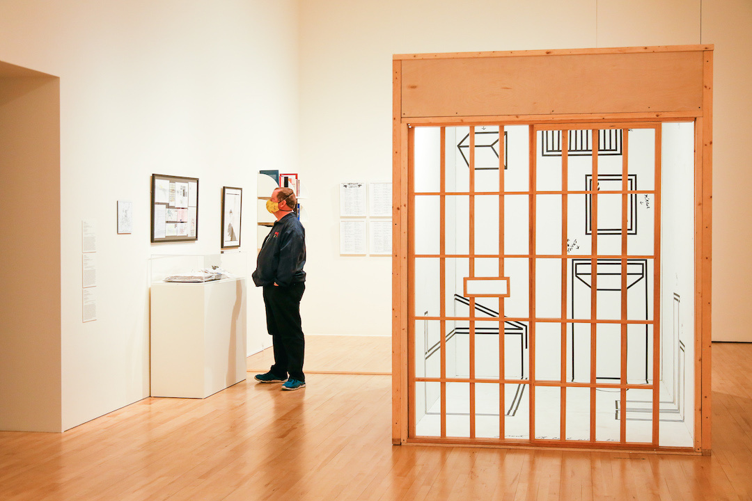 Man wearing mask in gallery looking at an installation piece.