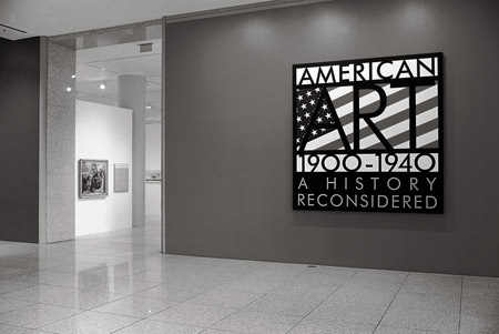A black and white photograph of a sign for the exhibition "American Art 1900–1940, A History Reconsidered." In the background there are two artworks hanging on the wall near the opening of the gallery.