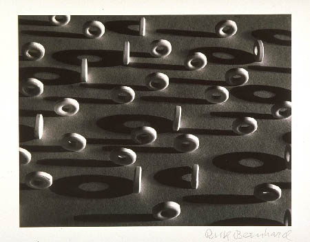 A black and white image of circular white lifesaver candies. They are sitting on their edges, casting shadows. The angle is taken from above, at a bit of a distance, making them look like tiny white car tires.