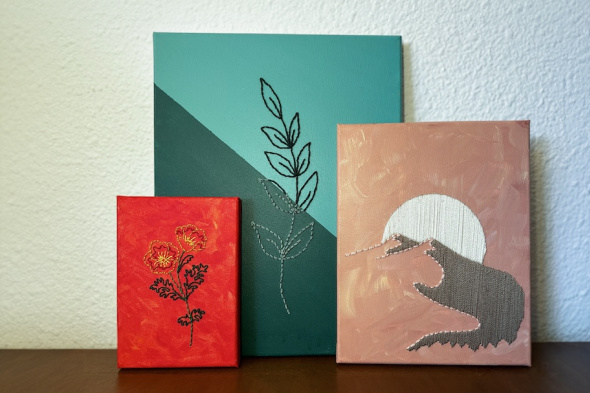 three painted canvases with embroidered imagery of flowers, leaves and a mountain