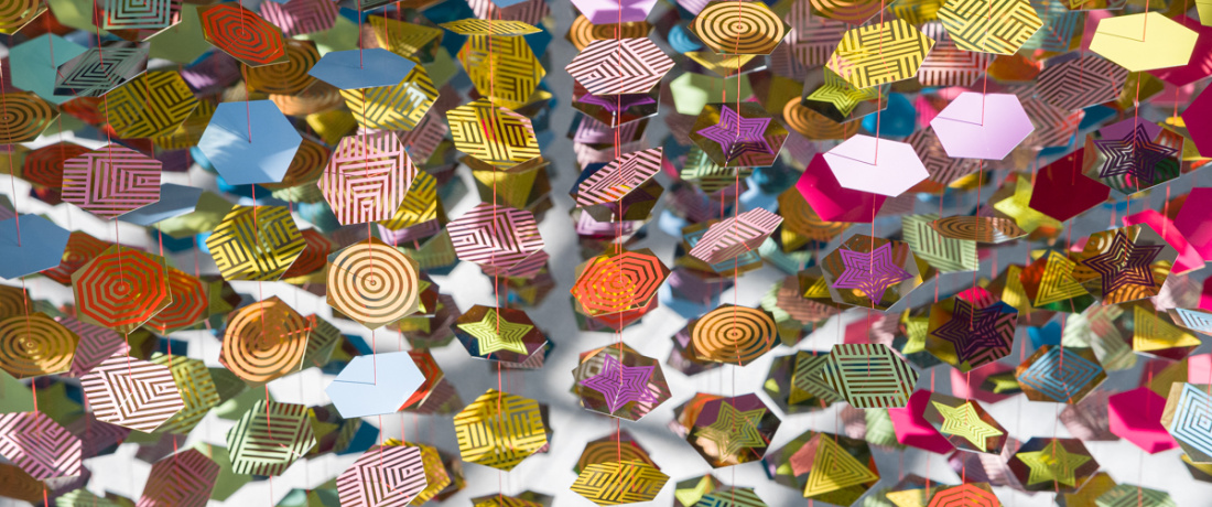 suspended hexagonal discs with a reflective surface with colored stars and geometric motifs