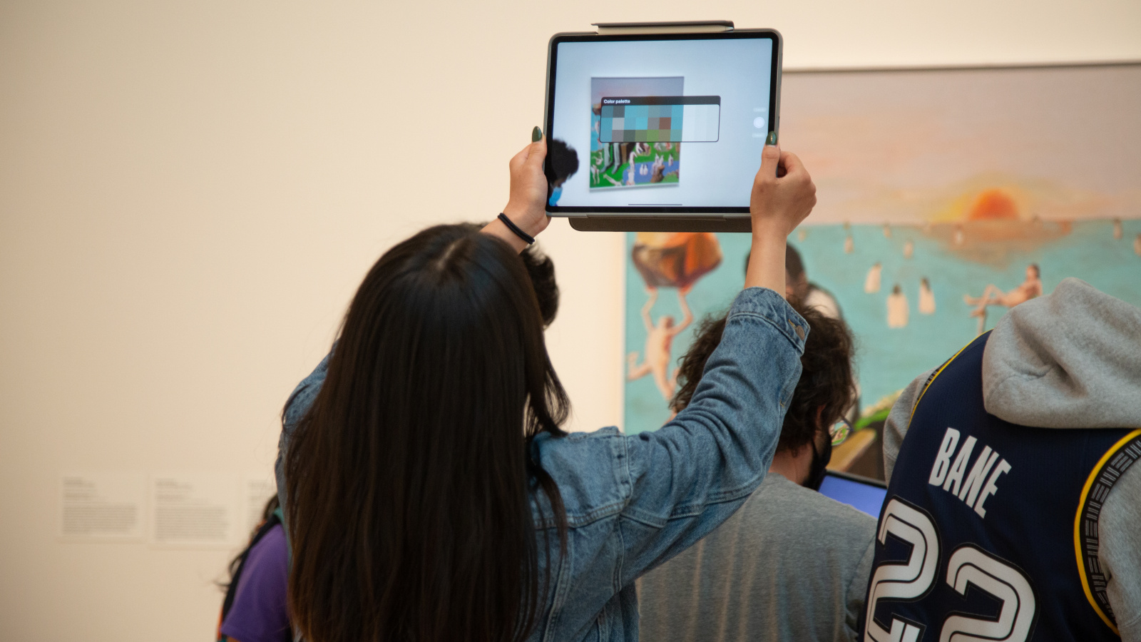 a visitor holding up a tablet in front of an artwork