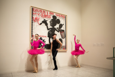 three ballet dancers in front of an artwork