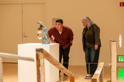 two visitors looking intently at a sculpture with a preserved angler fish