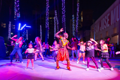 group dancing outside at night led by a Black dancer in a traditional costume