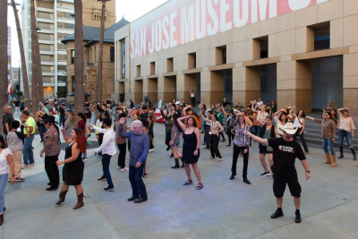 group of people dancing led by a White man wearing a western cowboy hat