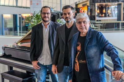 three musicians standing next to a grand piano