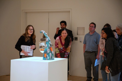 a tour group gazing upon an expressive ceramic sculpture with a preserved angler fish suspended