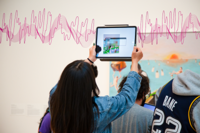 woman holding up a tablet in front of a painting with an overlay of sound wave illustrations 