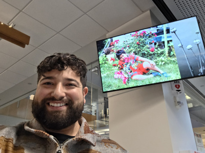 Bearded man taking a selfie with a digital monitor projecting photographs