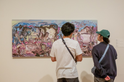 Two people looking at an expressive painting with figures in a landscape
