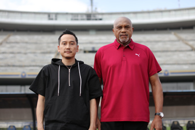 Middle aged asian man with older black man stand together in a stadium