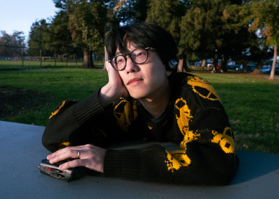 chinese american young man wearing glasses in a park