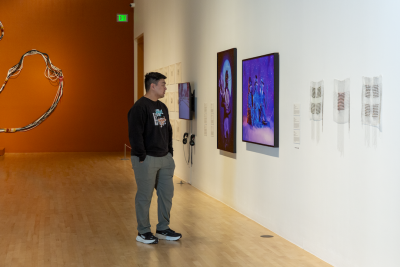 asian man in gallery looking at a vibrant photographic print