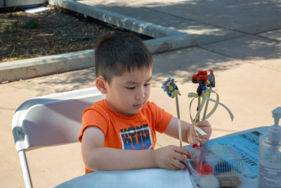 young vietnamese boy holding up miniature clay figurines on sticks