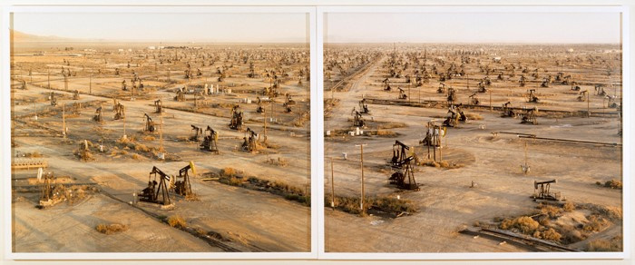 Two prints showing one extended scene: hundreds of black oil rigs surrounded by dirt roads and telephone wires, with small tufts of grass all that remains of the original landscape.