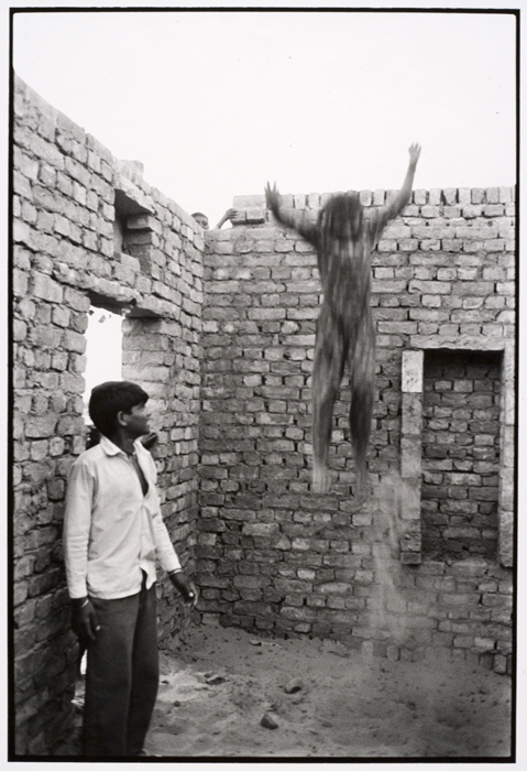 Within a small brick room, with no ceiling and dirt floors is a playful, yet daring scene. The blurry photograph of a child mid-jump is contrasted by playmates watching excitedly. Although joyful, poverty and conflict emanate from the scene.