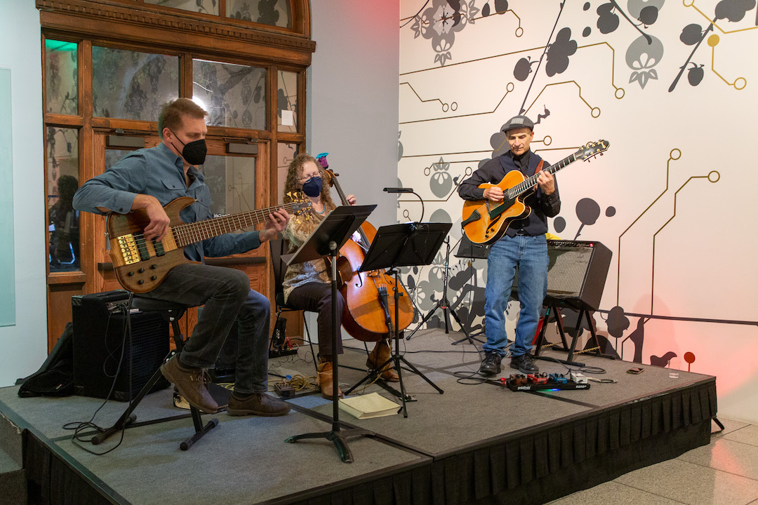 A band trio on stage inside a museum.