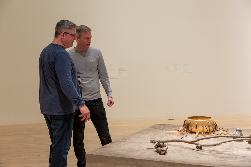 Two engaged visitors gazing upon materially hybrid works.