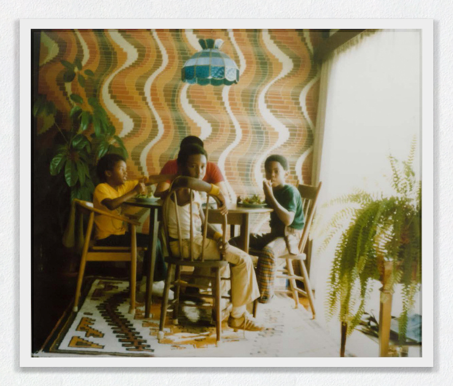 Three young Black boys and one Black man eating on a table.