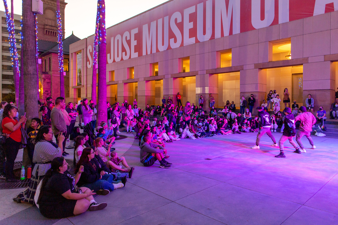 Group of dancers performing in front of an outdoor audience in front of a museum