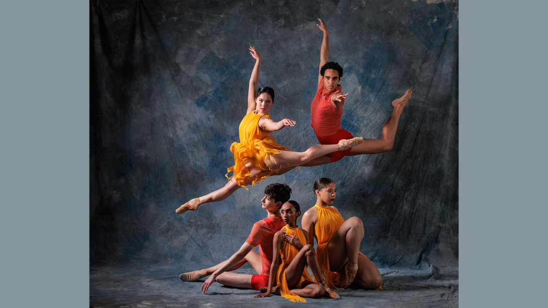 two dancers leaping midair with three dancers seated in a formation