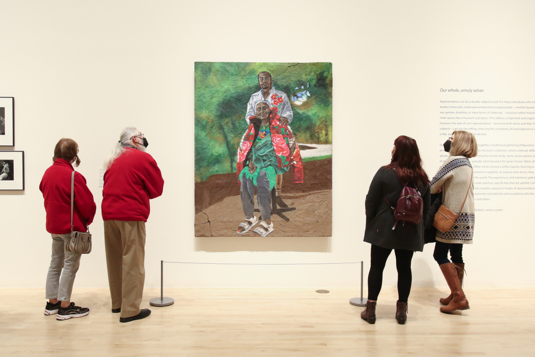 Visitors observe a portrait painting in an exhibition.