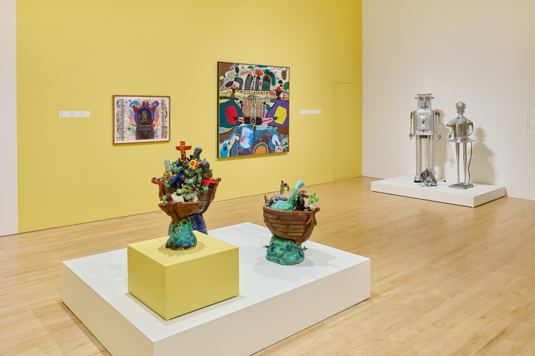 installation view of a gallery corner with robotic sculptures with two paintings on the wall and three ceramic sculptures of animals in front