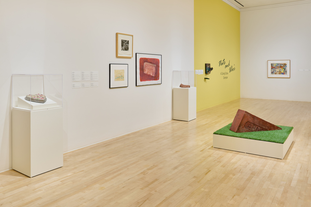 installation view of a gallery with works paper and a large brick sculpture in front