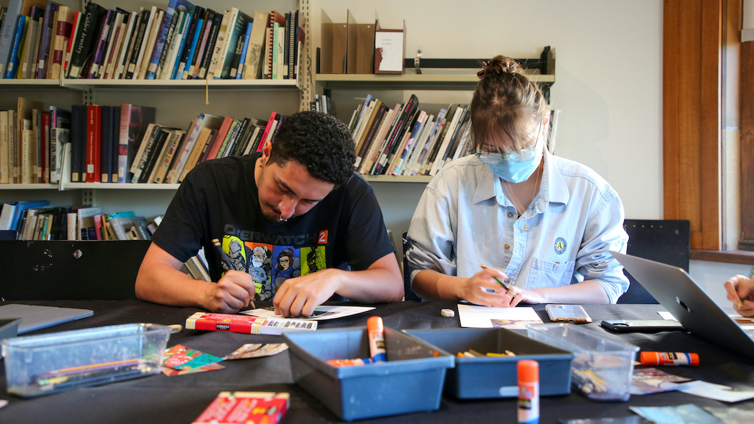 two workshop participants writing and drawing in a library