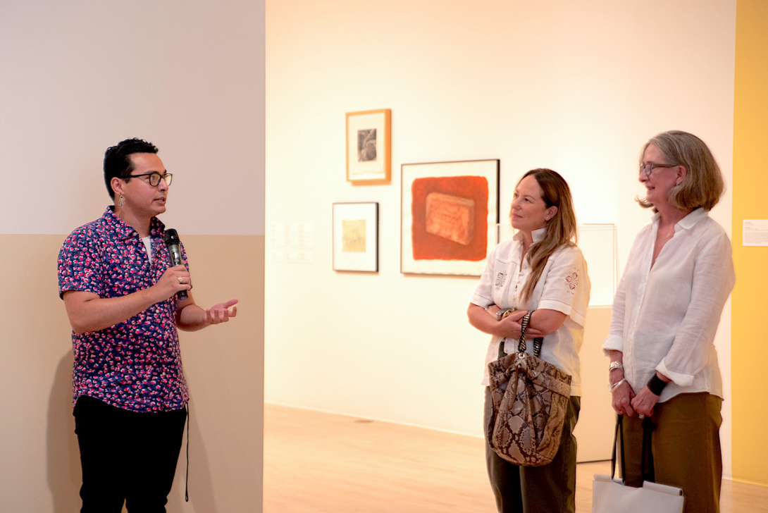 a latinx curator speaking to two visitors in a gallery