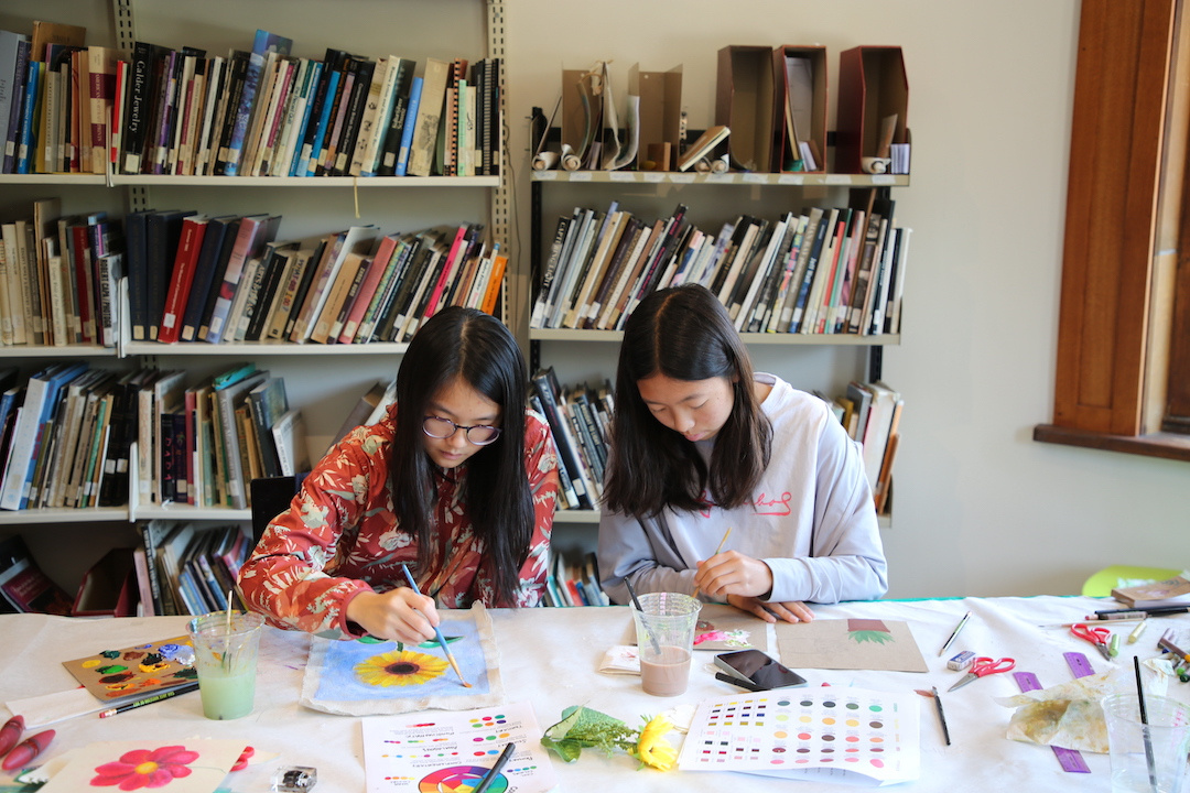 two teens painting flowers with watercolors