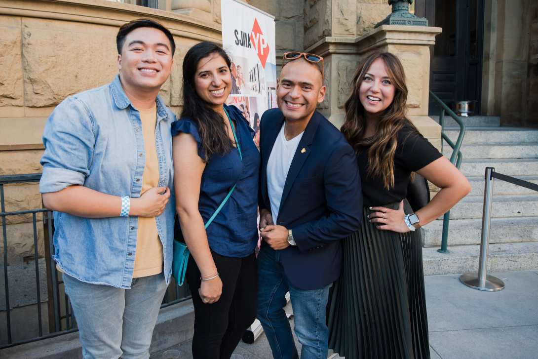 group of four young adults smiling in front of a historic building