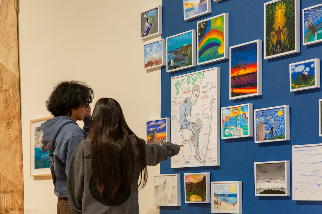 two young visitors looking at a wall of framed artworks