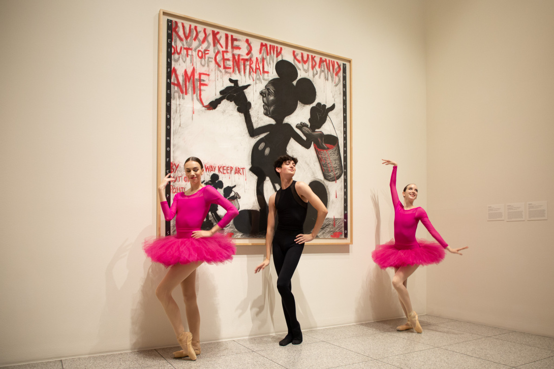 three ballet dancers in front of an artwork