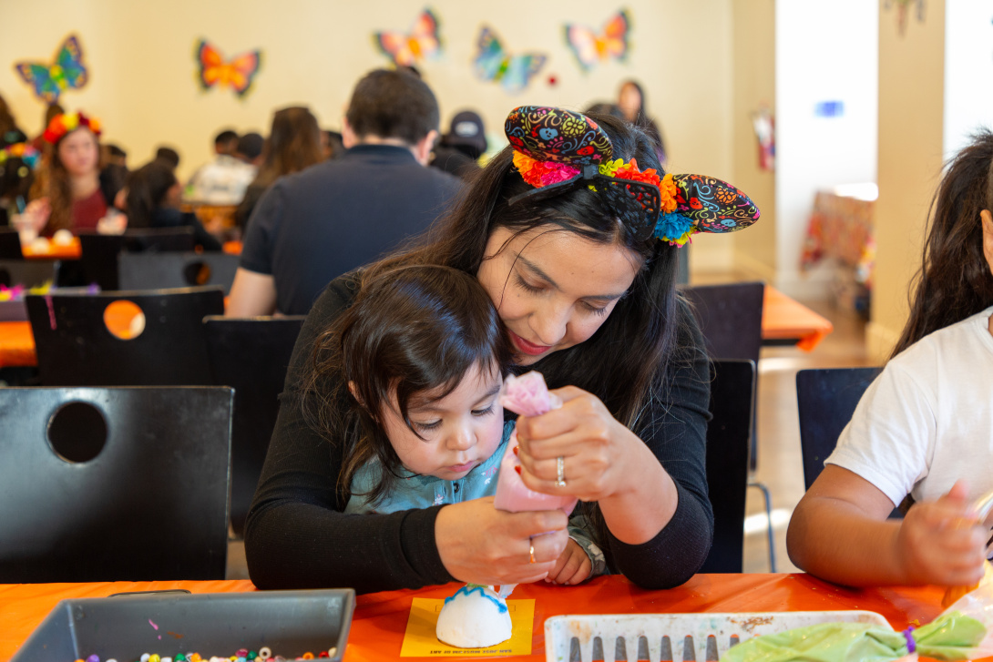 mother and toddler decorating a sugar skull together