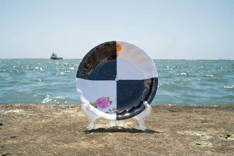 A vintage china plate on an easel by the ocean with a ship on the horizon