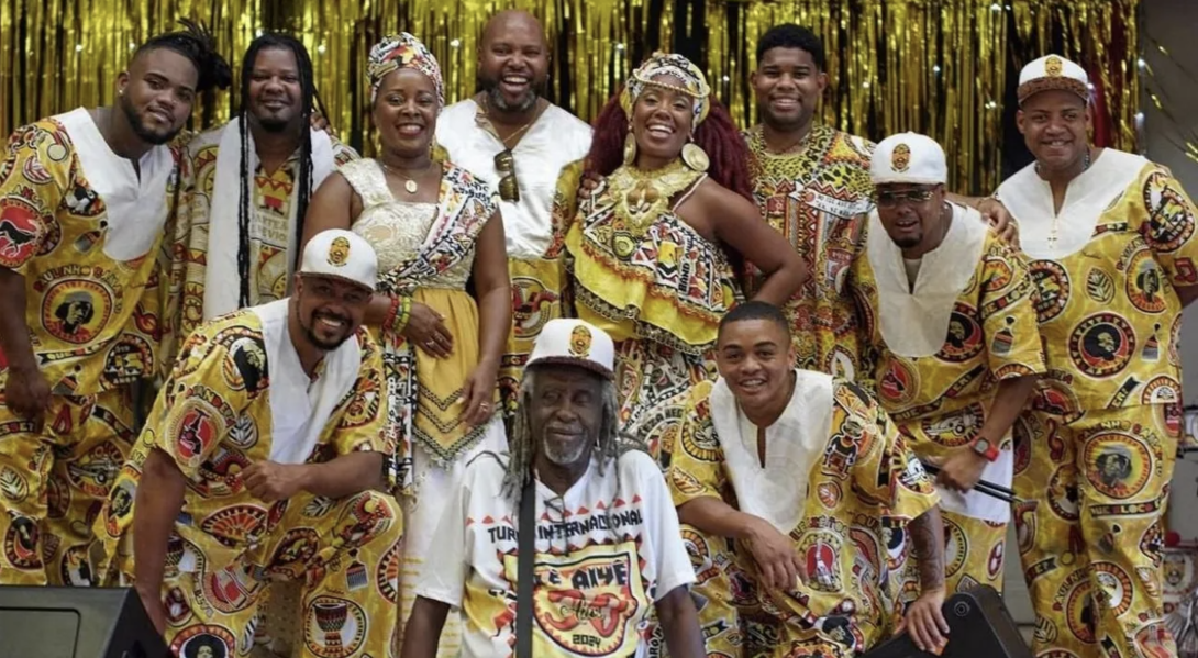 A group of Afro-Brazilian dancers wearing matching patterned outfits.