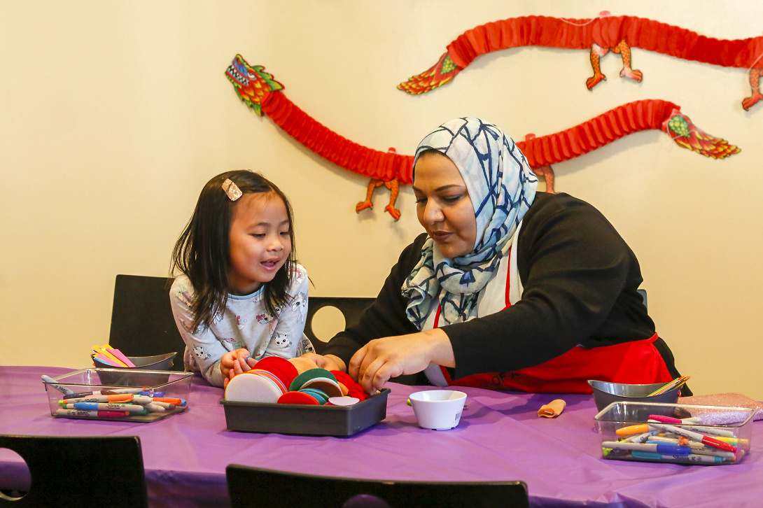 a woman wearing a hijab showing an art activity to a young girl