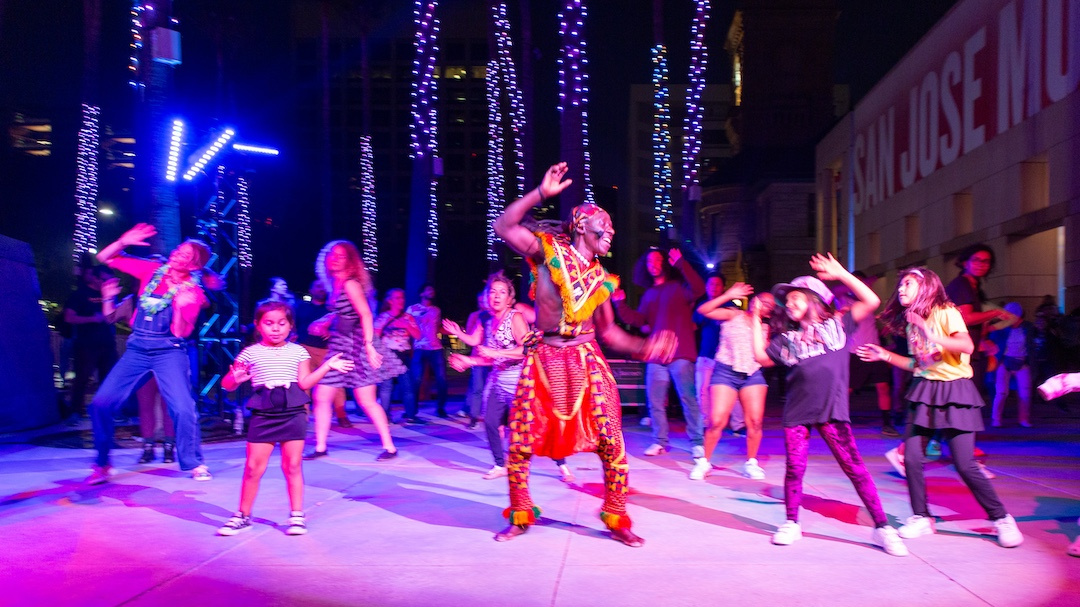 group of people dancing at night with an African male dancer