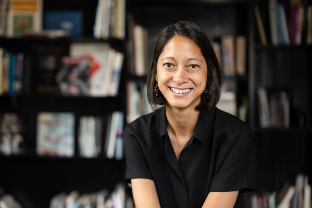 Mixed race Asian woman with short black bob with bookshelves behind her