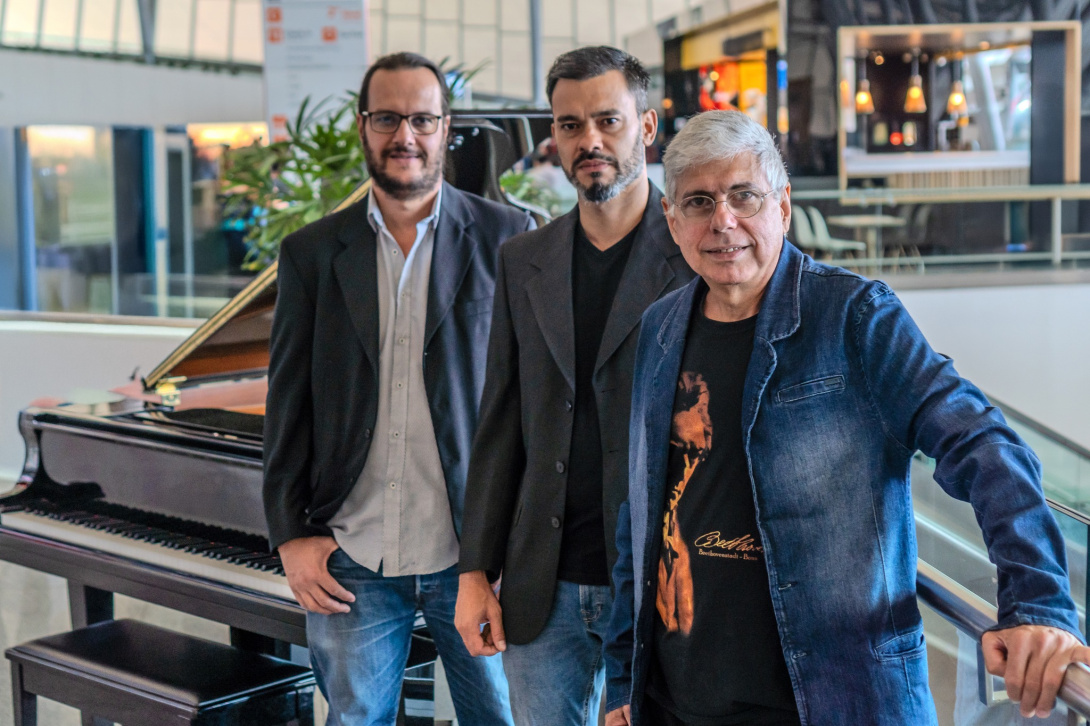 three musicians standing next to a grand piano