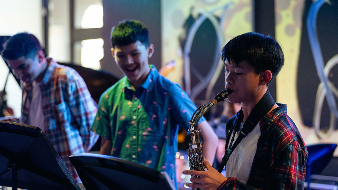 three young boys playing saxophone