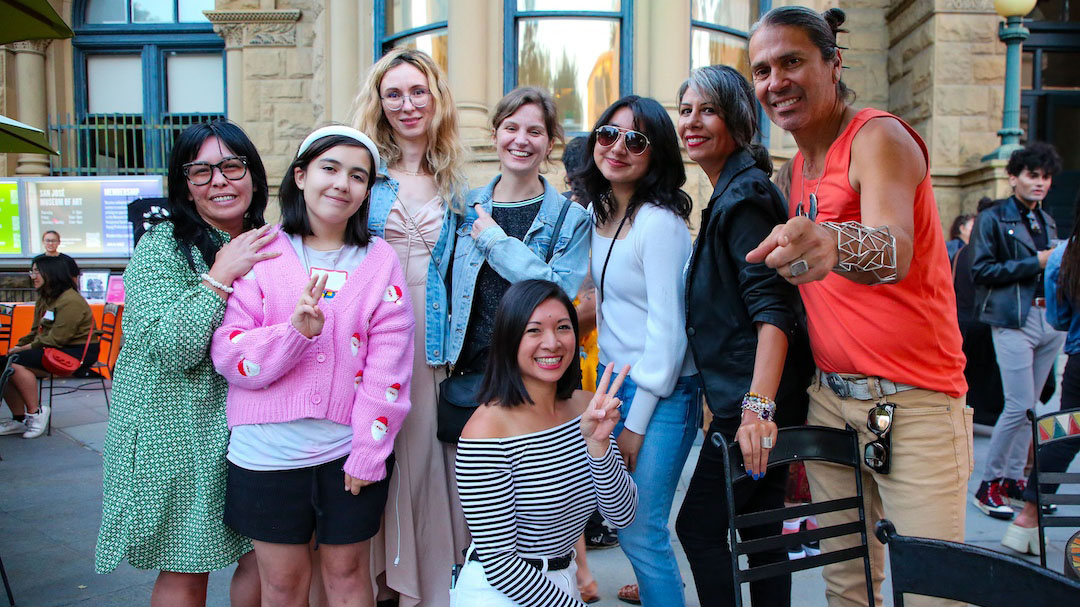 group of people posing with peace signs and one man pointing forward