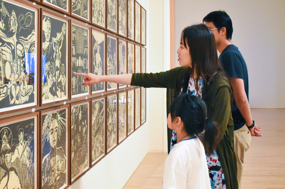 Visitors viewing framed artworks in a museum gallery