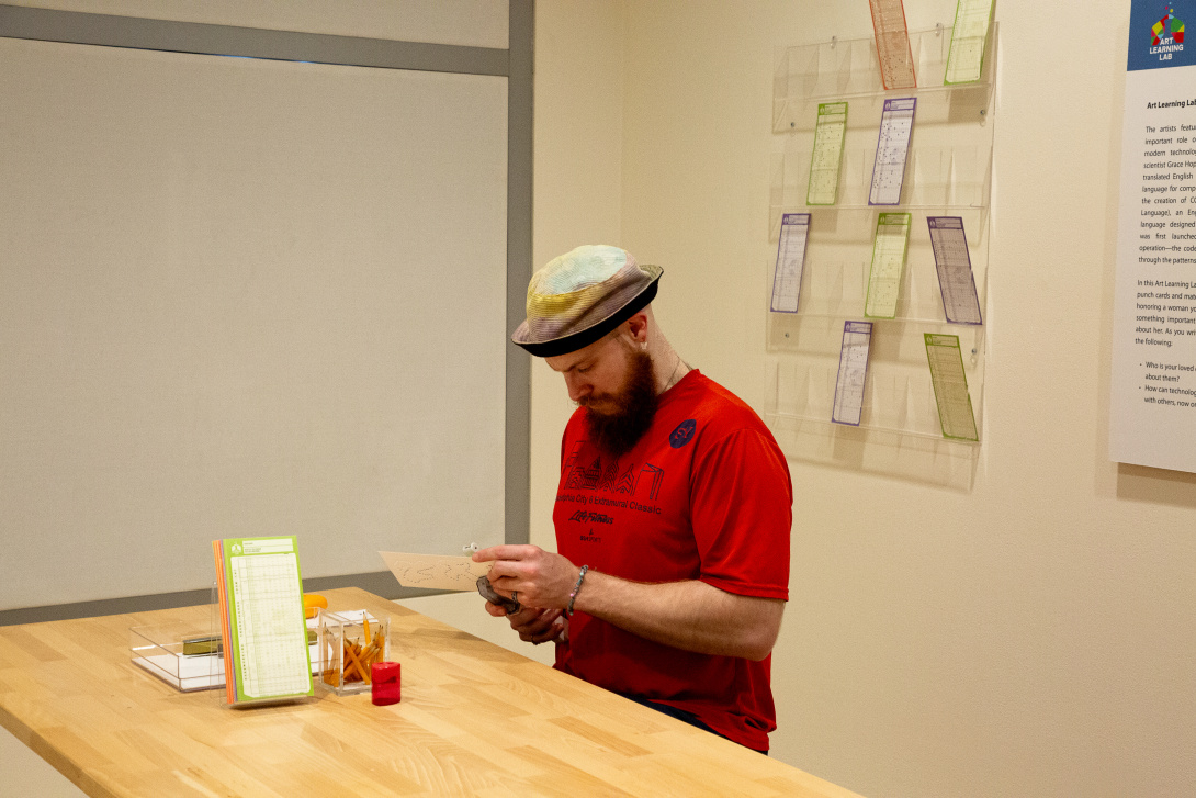 Visitor wearing headphones seated at a table in a gallery activity space.