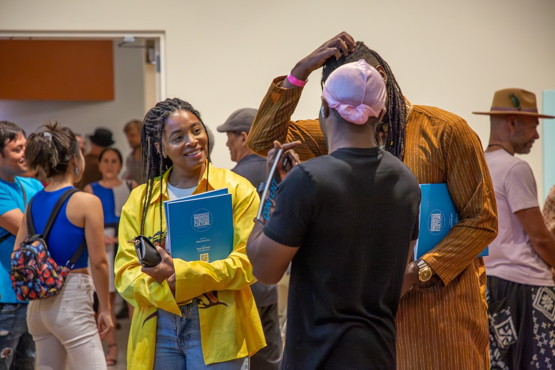 black woman with long braids holding up a Content Magazine with other folks