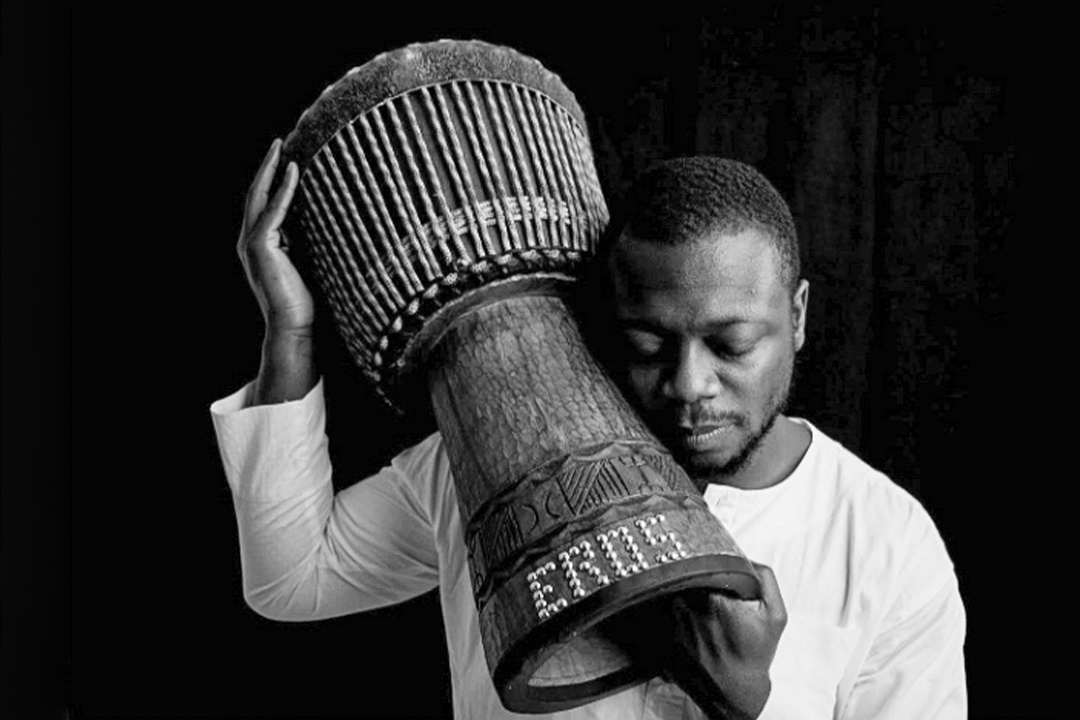west african man holding up a drum on his shoulder