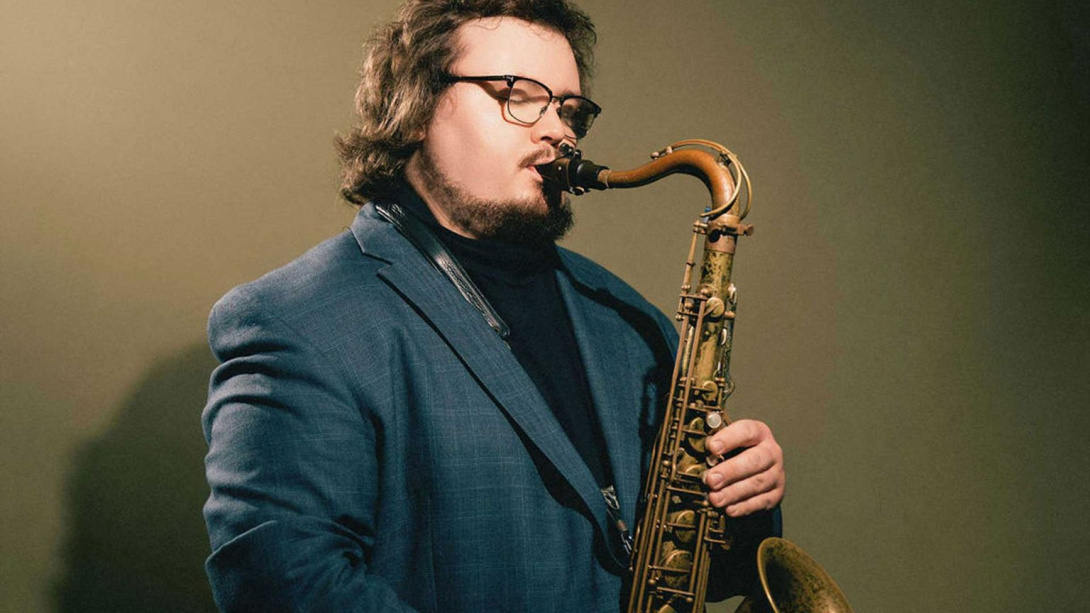 man wearing glasses playing the saxophone